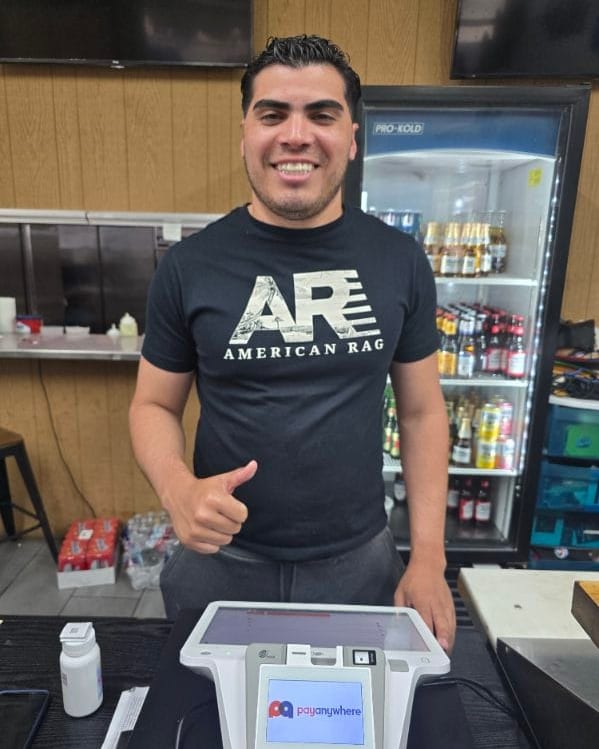 A team member at Alma Llanera Restaurant gives a thumbs up behind a new payment terminal