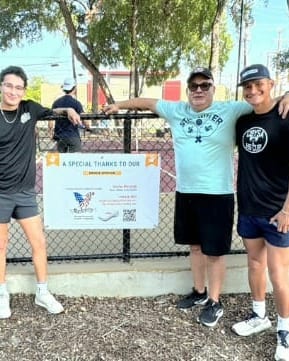 Tournament players standing beside a sponsor thank-you banner