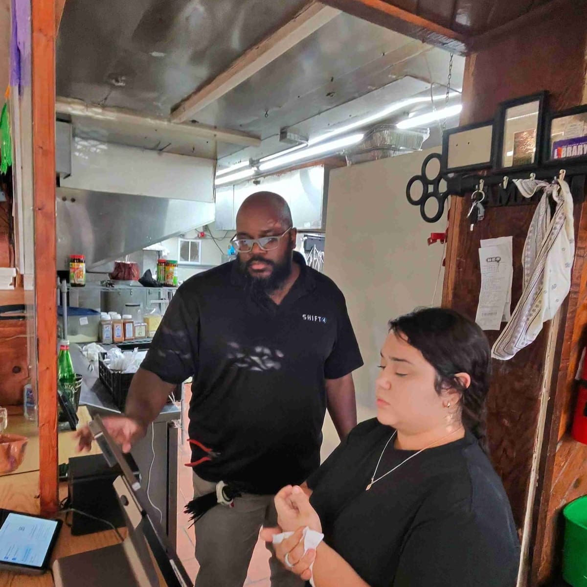 A technician trains a restaurant employee on a new point-of-sale system