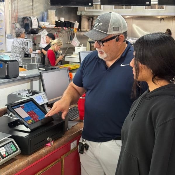 A team member is shown how to use the register at La Moreliana Meat Market